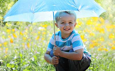 A young boy smiling under an umbrella