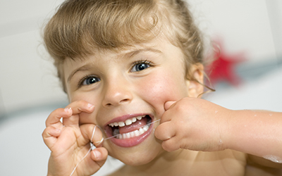 Young girl cleaning teeth with dental floss