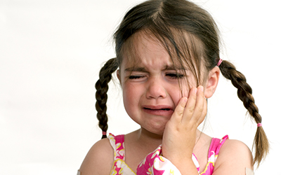 A young girl holding her mouth crying