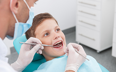 A young boy sitting in a dental chair while having his teeth looked at