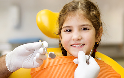 A girl smiling while sitting in a dental chair