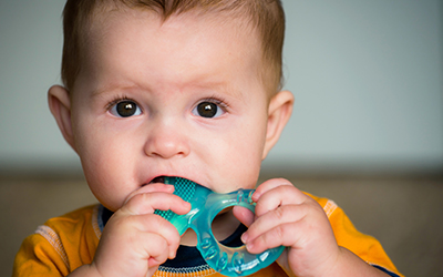 A young baby teething on a teething ring