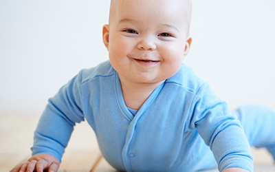 A young boy crawling while smiling