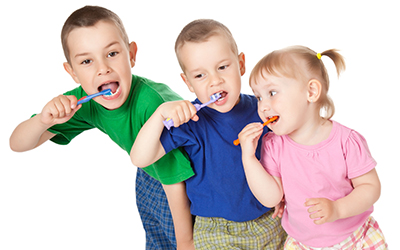 Three young kids brushing their teeth together