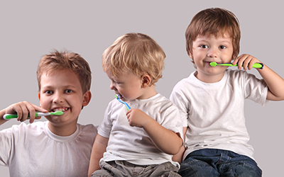 Three young kids brushing their teeth