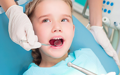 A young girl having her teeth looked at by the dentist